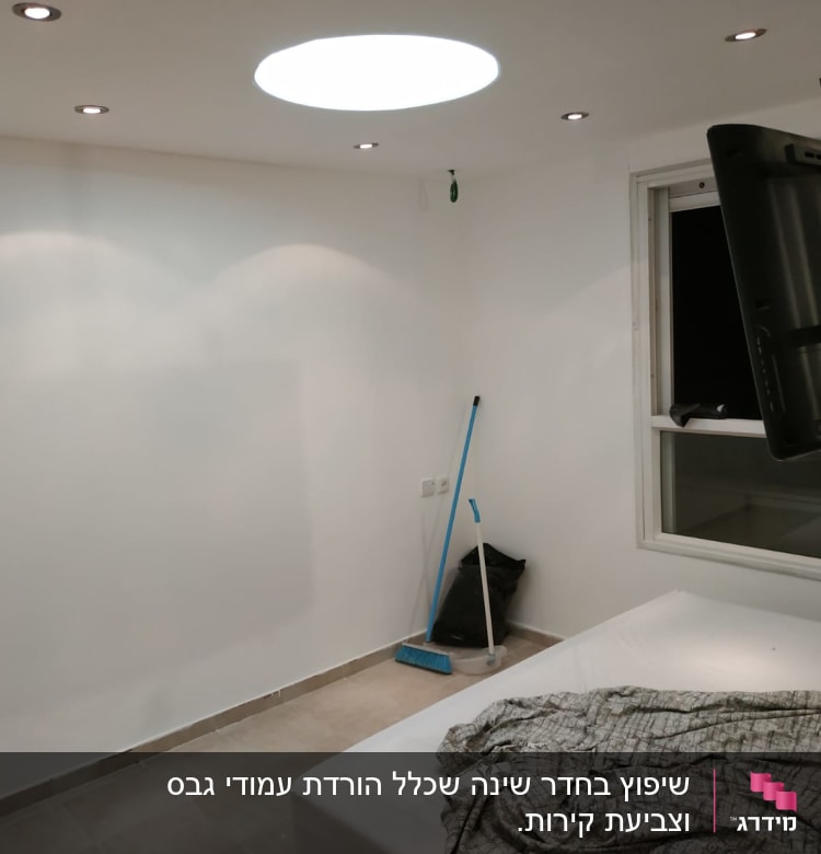 חדר עם טלוויזיה תלויה, מטאטא ושקית אשפה